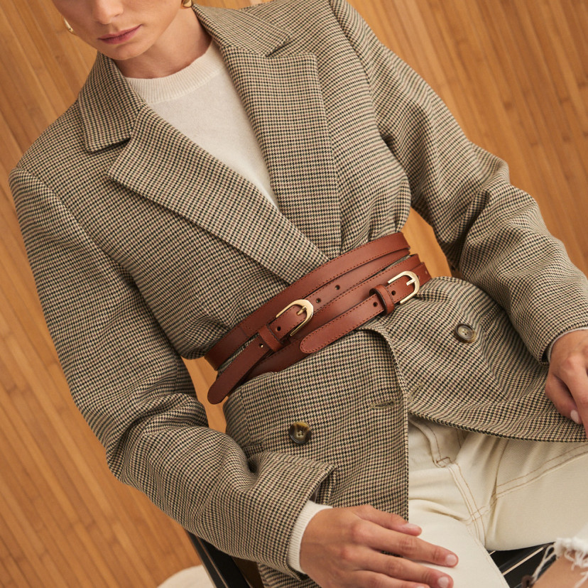 Double loop leather belt in leather color with front view over houndstooth jacket, seated model - MONPIEL