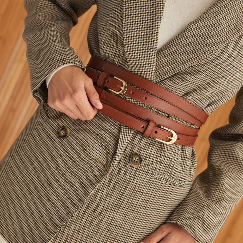 Double loop leather belt in leather color with front view, hand holding the belt, slightly tilted image - MONPIEL