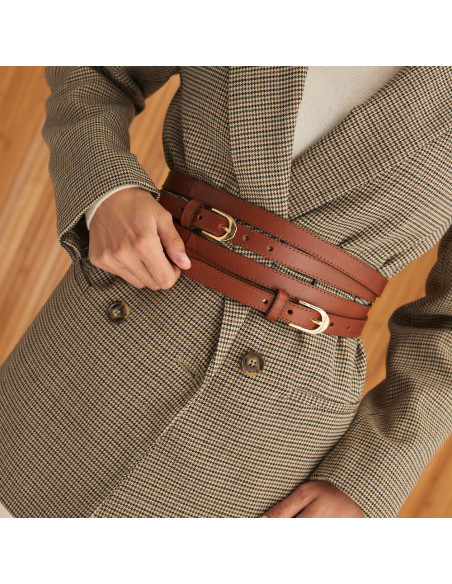 Cintura a doppio giro in pelle color cuoio, vista frontale, mano che tiene la cintura, immagine leggermente inclinata - MONPIEL Cintura a doppio giro in pelle color cuoio, vista frontale, mano che tiene la cintura, immagine leggermente inclinata - MONPIEL