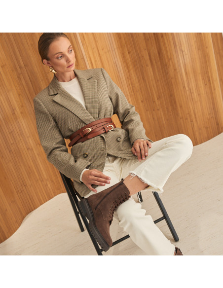 Stivaletto con lacci Camila in pelle scamosciata marrone, piano generale del modello seduto sulla sedia con la gamba i - MONPIEL Stivaletto con lacci Camila in pelle scamosciata marrone, piano generale del modello seduto sulla sedia con la gamba i - MONPIEL