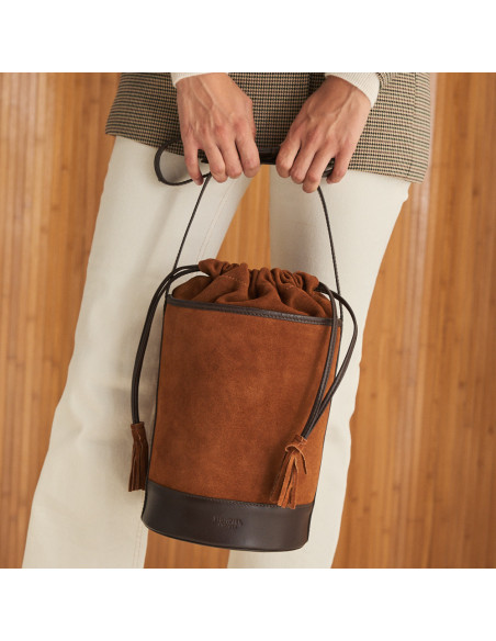 Round cube-shaped leather bag in suede leather colour with front view, closed and held with hands - MONPIEL