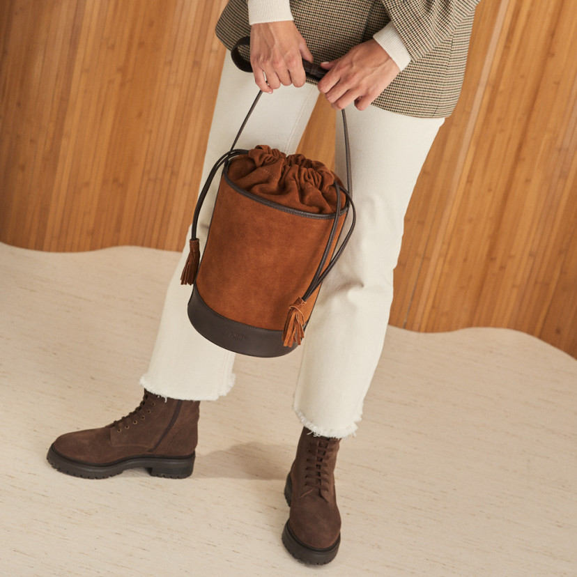 Round cube-shaped leather bag in suede leather color, held with both hands, front view - MONPIEL