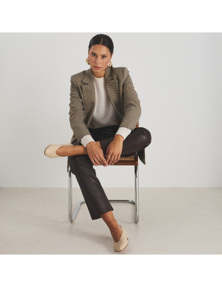 Ballerina con tacco in pelle beige, modello seduto su una sedia, vista frontale, piano generale - MONPIEL Ballerina con tacco in pelle beige, modello seduto su una sedia, vista frontale, piano generale - MONPIEL