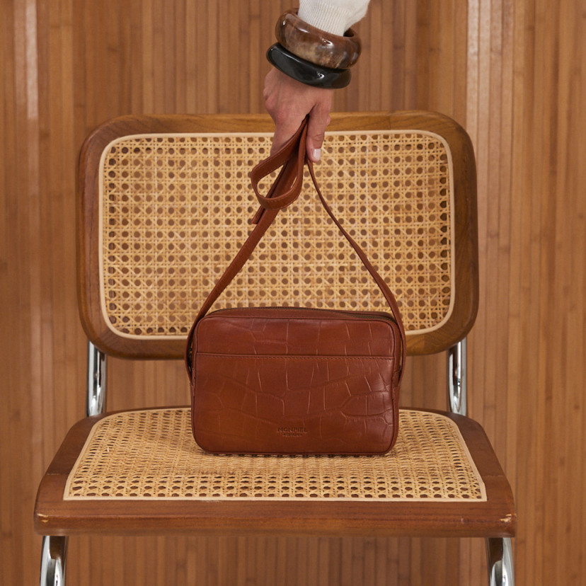 Bolsa transversal em couro coco na cor couro, vista frontal sobre a cadeira - MONPIEL