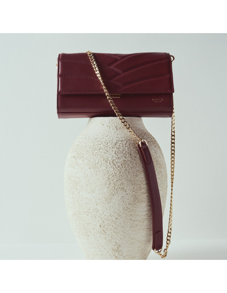 Bolso cartera de mano de piel mujer venecia en color burdeos con vista frontal encima de jarrón - MONPIEL