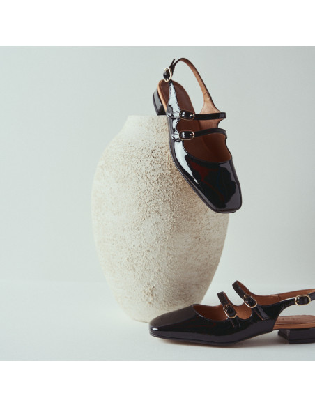 Mary Jane sans talon Lolina en cuir noir, vue de profil et en perspective, talon reposant sur un vase - MONPIEL Mary Jane sans talon Lolina en cuir noir, vue de profil et en perspective, talon reposant sur un vase - MONPIEL