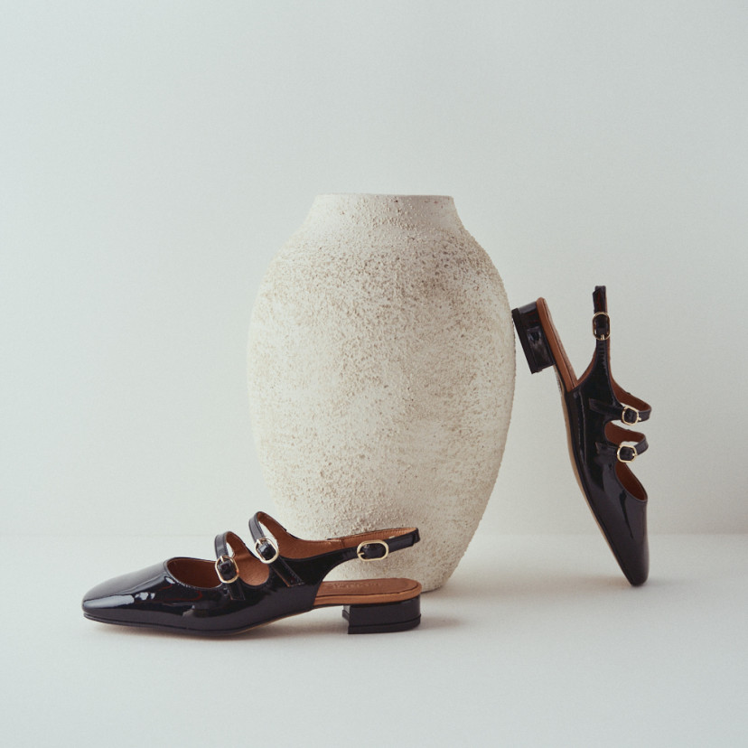 Lolina backless Mary Jane in black with side view, heel resting on the vase - MONPIEL