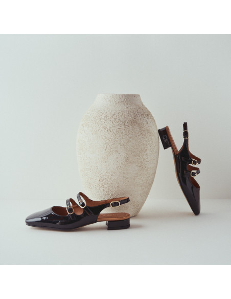 Mary Jane sans talon Lolina en cuir noir, vue de profil, talon reposant sur un vase - MONPIEL Mary Jane sans talon Lolina en cuir noir, vue de profil, talon reposant sur un vase - MONPIEL