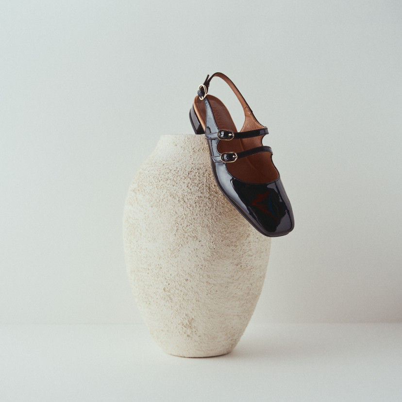 Lolina backless Mary Jane in black with heel resting on a vase and white background - MONPIEL
