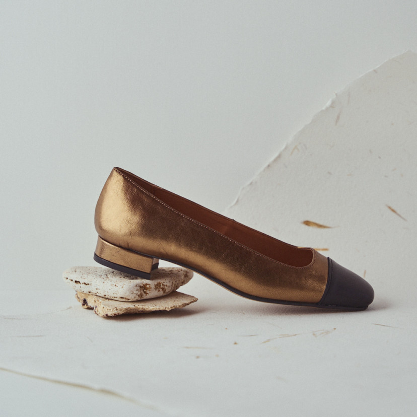 Women's square-toe leather shoe in ochre with close-up heel detail resting on stones - MONPIEL