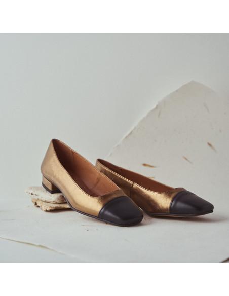 Women's square-toe leather shoe in ochre with close-up heel detail resting on stones, perspective view - MONPIEL Women's square-toe leather shoe in ochre with close-up heel detail resting on stones, perspective view - MONPIEL