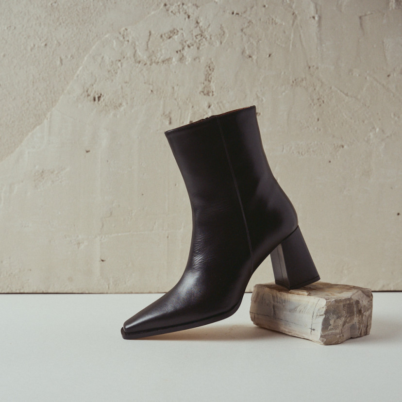 Black leather heeled boot with side view resting on a rock - MONPIEL