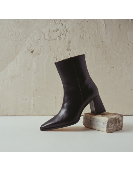 Black leather heeled boot, profile view, resting on a rock - MONPIEL Black leather heeled boot, profile view, resting on a rock - MONPIEL