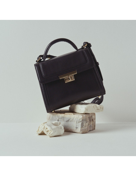 60's leather women’s bag in black with front view resting on rocks - MONPIEL