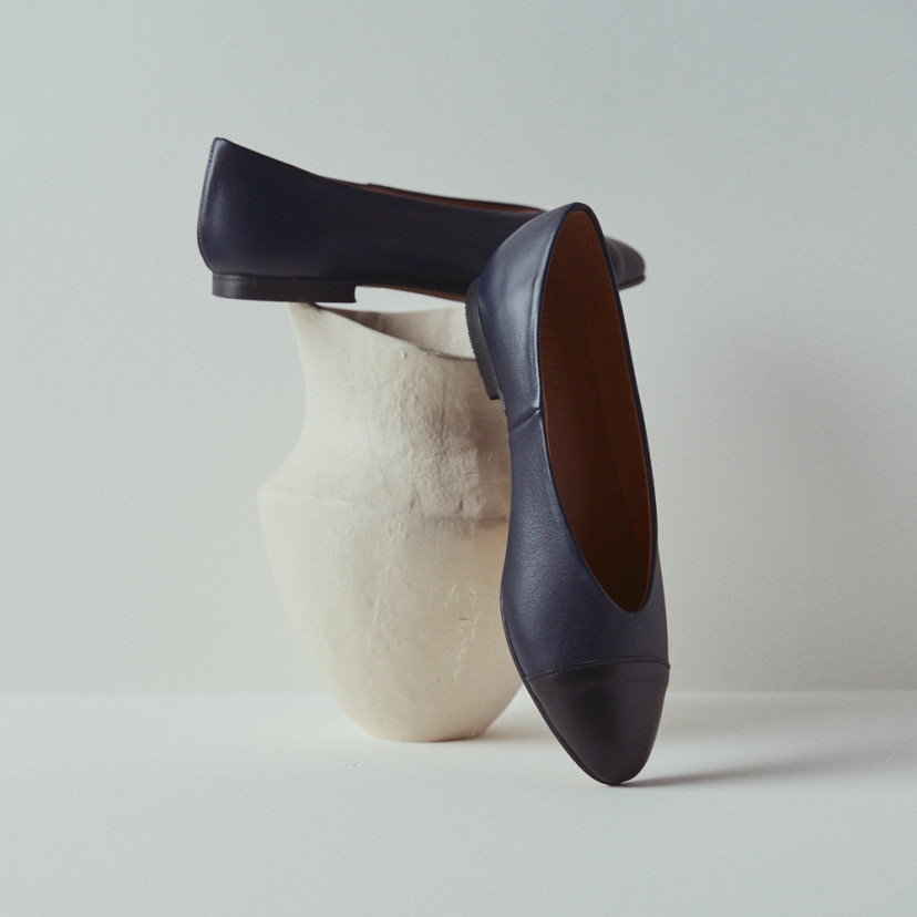 Ameliè flat ballerina with black-navy toe, toe resting in perspective, close-up on a vase - MONPIEL
