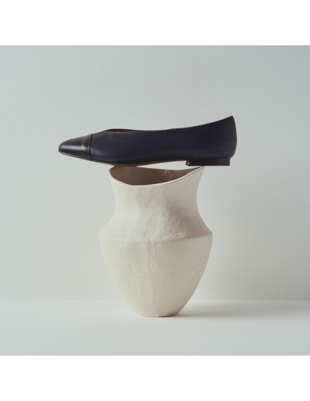 Ameliè flat ballerina with black-navy toe, side view in close-up resting on a vase - MONPIEL Ameliè flat ballerina with black-navy toe, side view in close-up resting on a vase - MONPIEL