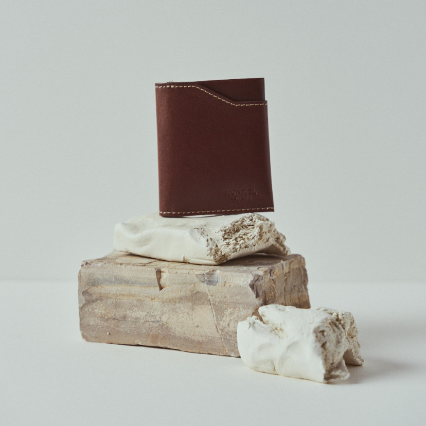 Leather pocket wallet in leather color with front view resting on rocks - MONPIEL