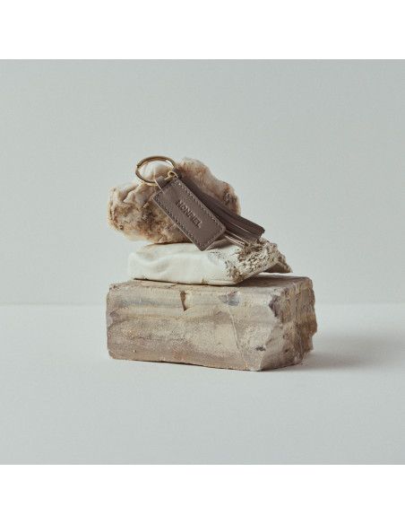 Taupe leather tassel keyring resting on rocks - MONPIEL