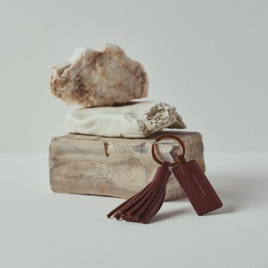 Portachiavi con nappina in pelle color cuoio, appoggiato su rocce - MONPIEL 2