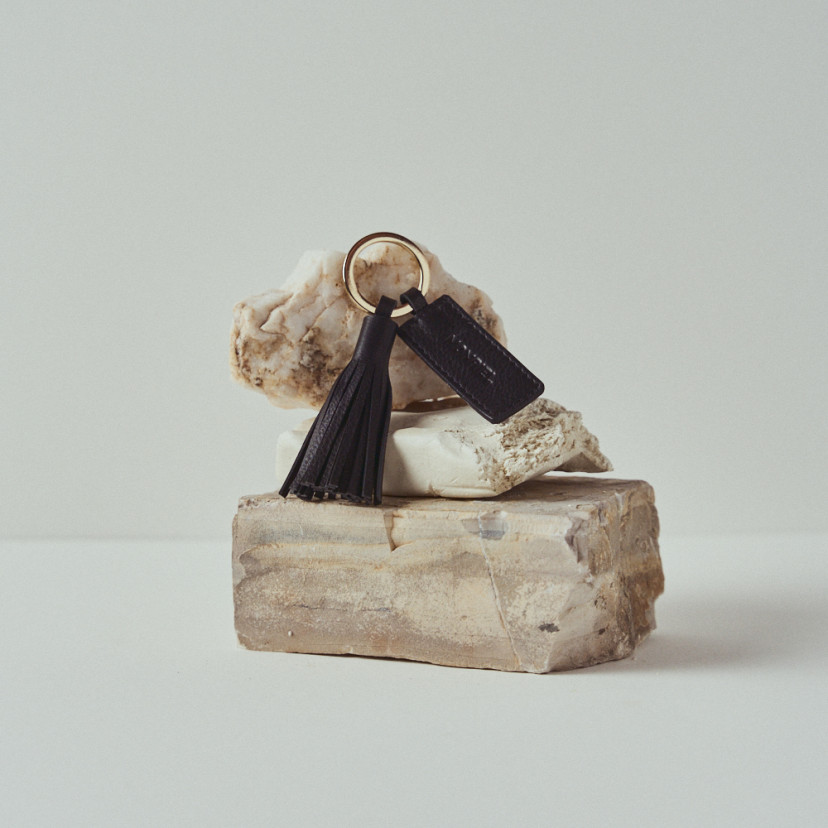 Leather tassel keychain in black resting on rocks - MONPIEL