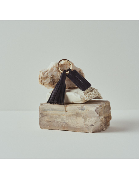 Leather tassel keychain in black resting on rocks - MONPIEL Leather tassel keychain in black resting on rocks - MONPIEL