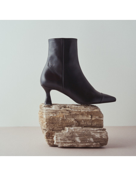 Jimena pointed-toe leather boot in black with side view resting on a rock in close-up - MONPIEL