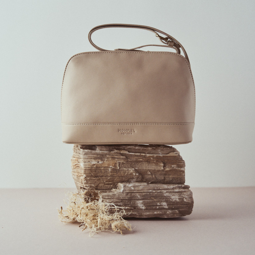 Medium leather bag in beige with front view resting on a rock - MONPIEL