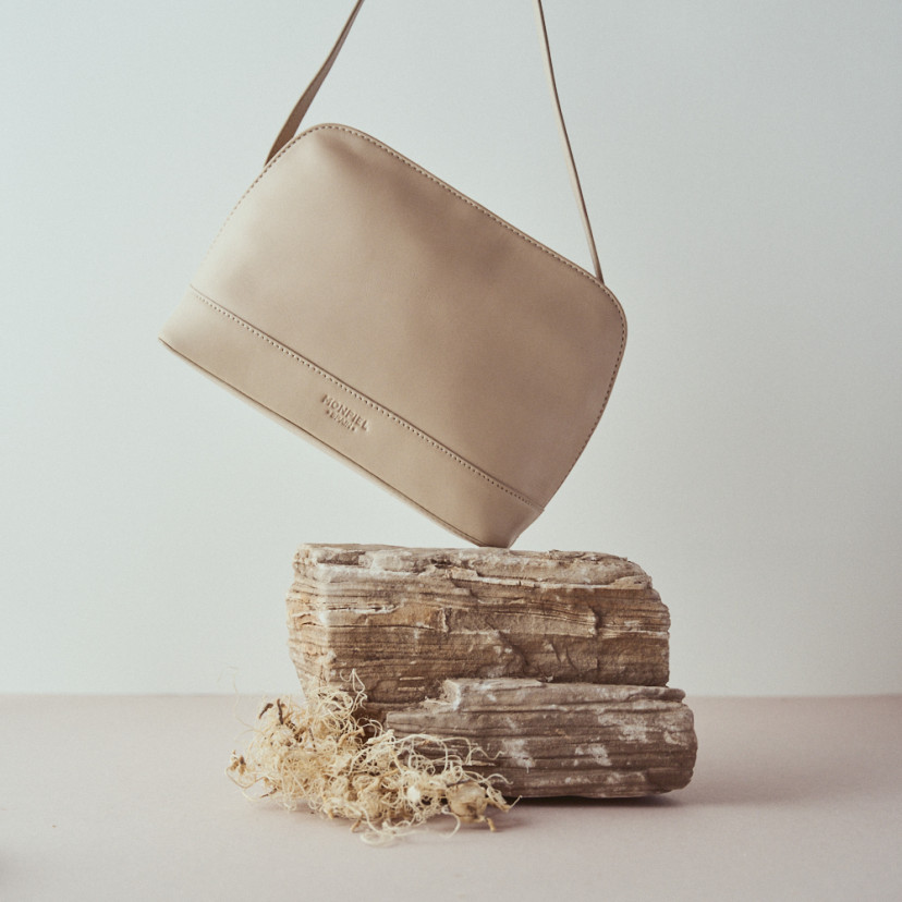 Medium leather bag in beige with front view, tilted over the rock - MONPIEL