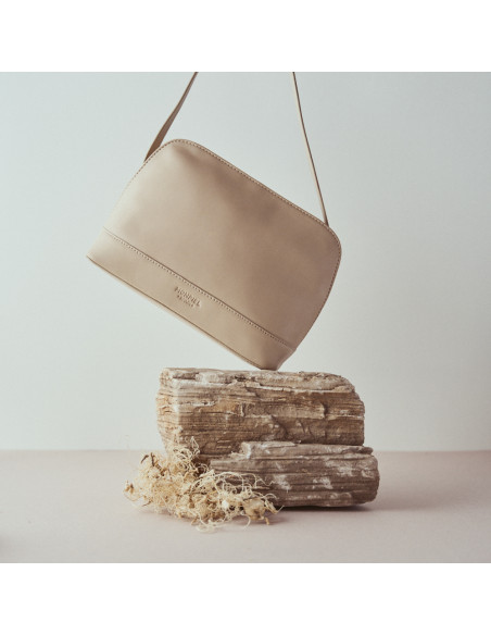 Bolso mediano de piel en color beige con vista frontal inclinado sobre la roca - MONPIEL Bolso mediano de piel en color beige con vista frontal inclinado sobre la roca - MONPIEL