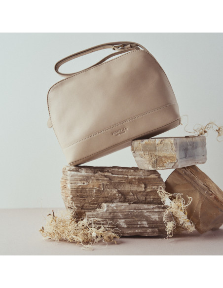 Bolsa média de couro na cor bege, vista frontal, bolsa inclinada sobre pedras - MONPIEL Bolsa média de couro na cor bege, vista frontal, bolsa inclinada sobre pedras - MONPIEL