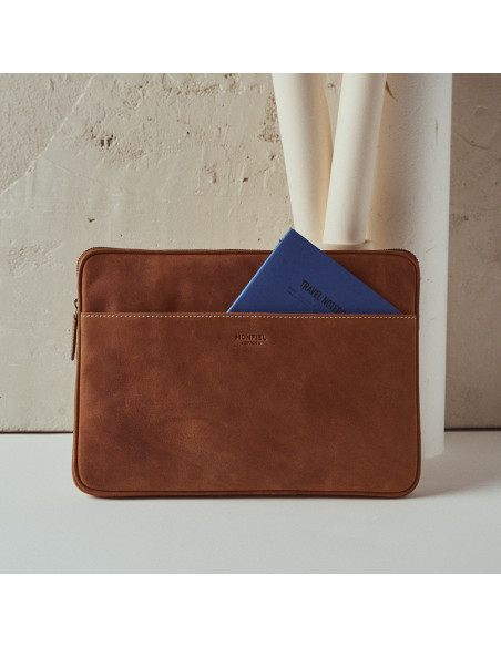Custodia per laptop in pelle color cuoio per dispositivi da 15" pollici, vista frontale, appoggiata su un vaso con una - MONPIEL