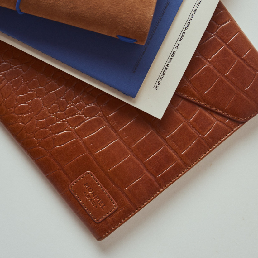 Capa de notebook de couro Elegance Coco na cor couro com livros por cima - MONPIEL