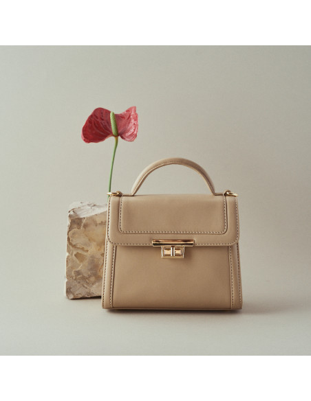 Petit sac à main en cuir beige pour femme, style 60's, vue frontale, à côté d'une fleur - MONPIEL