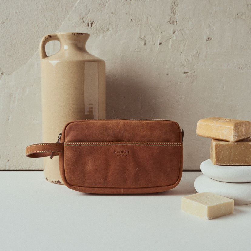 Men's leather toiletry bag in Havana colour with front view resting on a vase - MONPIEL