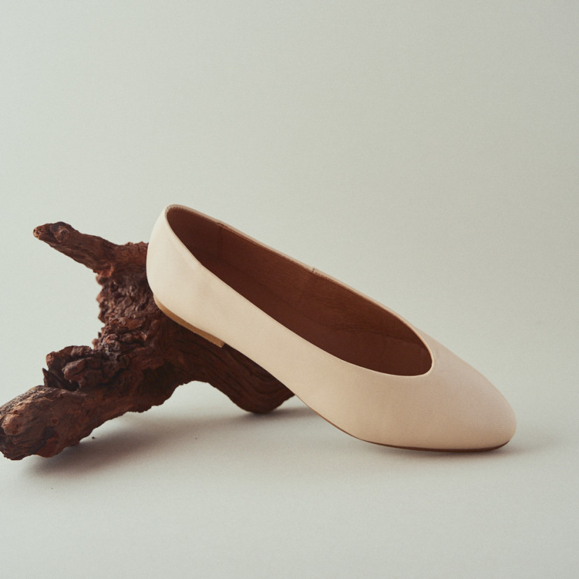 Beige flat ballerina with front view and perspective, resting on a branch with white background - MONPIEL