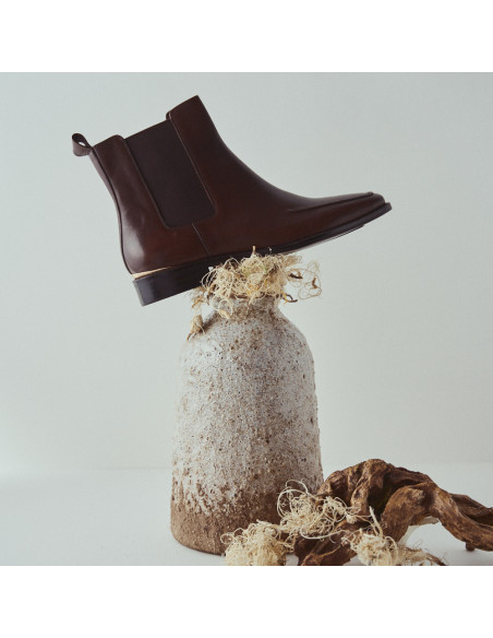 Luisa brown leather Chelsea boot with side view on top of a vase - MONPIEL Luisa brown leather Chelsea boot with side view on top of a vase - MONPIEL
