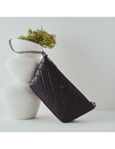 Small women's leather quilted New York bag in black with front view resting on a vase - MONPIEL