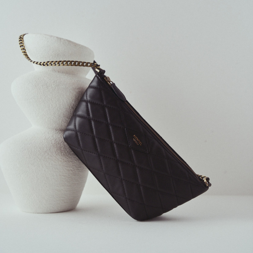 Small women's leather quilted New York bag in black resting on a vase - MONPIEL