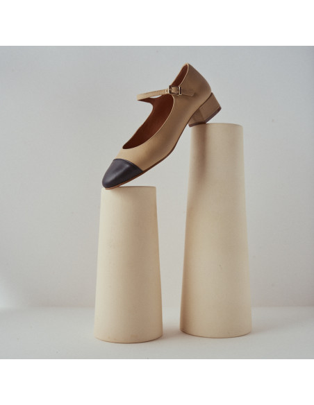 Beige Charlotte Mary Jane with cap toe, profile view, resting on two vases - MONPIEL Beige Charlotte Mary Jane with cap toe, profile view, resting on two vases - MONPIEL