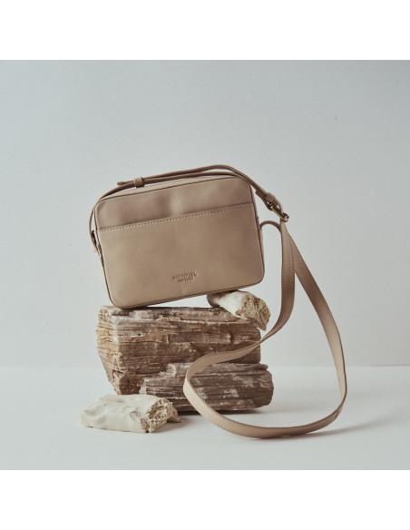 Beige Ledertasche mit Schultergurt-Detail, auf Felsen abgestützt - MONPIEL