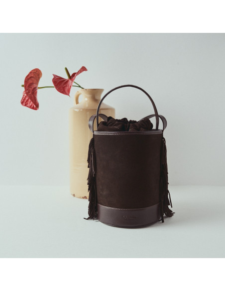 Bolso de cubo de piel flecos pequeño Roma en color marrón serraje con vista frontal delante de jarrón con flor - MONPIEL