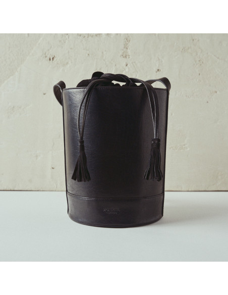 Round cube-shaped leather bag in black with front view, wall background - MONPIEL