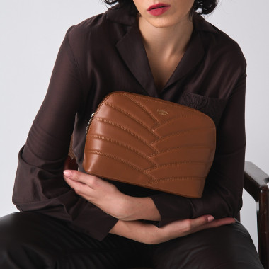 Borsa imbottita in pelle color cuoio con catena dorata, accanto a saponette - MONPIEL 2