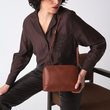 Medium leather bag in tan color, front view, tilted and resting on a vase - MONPIEL 2