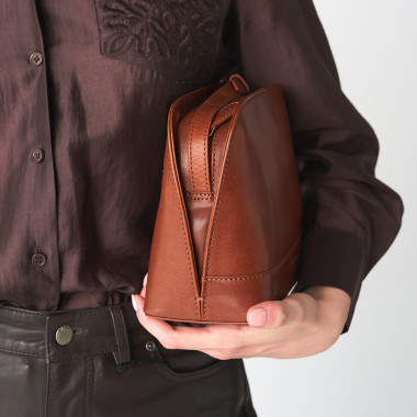 Medium leather bag in tan color, front view, tilted and resting on a vase - MONPIEL 2