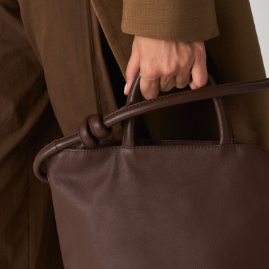 Bolsa grande com nós de couro na cor couro com vista frontal, alça curta segurada na mão - MONPIEL 2