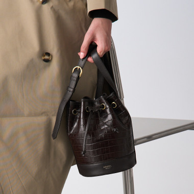 Small tan leather bucket bag, front view, next to a vase - MONPIEL 2