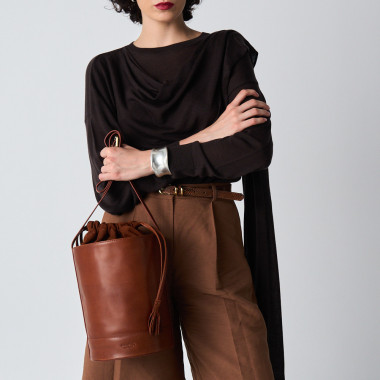 Sac rond en forme de seau de couleur havane, vue de face posé sur un meuble, avec un miroir en arrière-plan - MONPIEL 2
