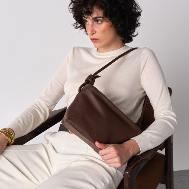 Bolsa pequena de couro com nós na cor taupe, vista frontal e detalhe da alça, apoiada sobre uma rocha - MONPIEL 2