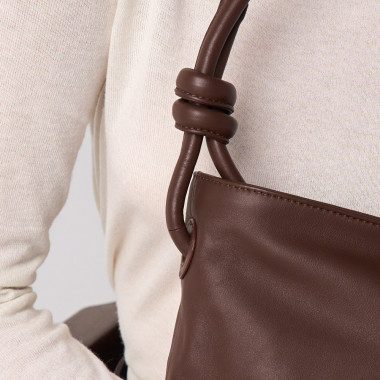 Bolsa pequena de couro com nós na cor taupe, vista frontal e detalhe da alça, apoiada sobre uma rocha - MONPIEL 2